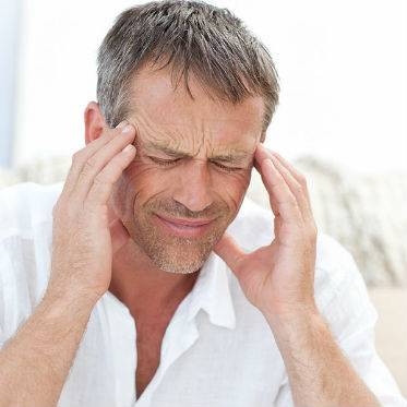 A man suffering from severe headaches caused by TMJ/TMD disorder rubs his temples.	